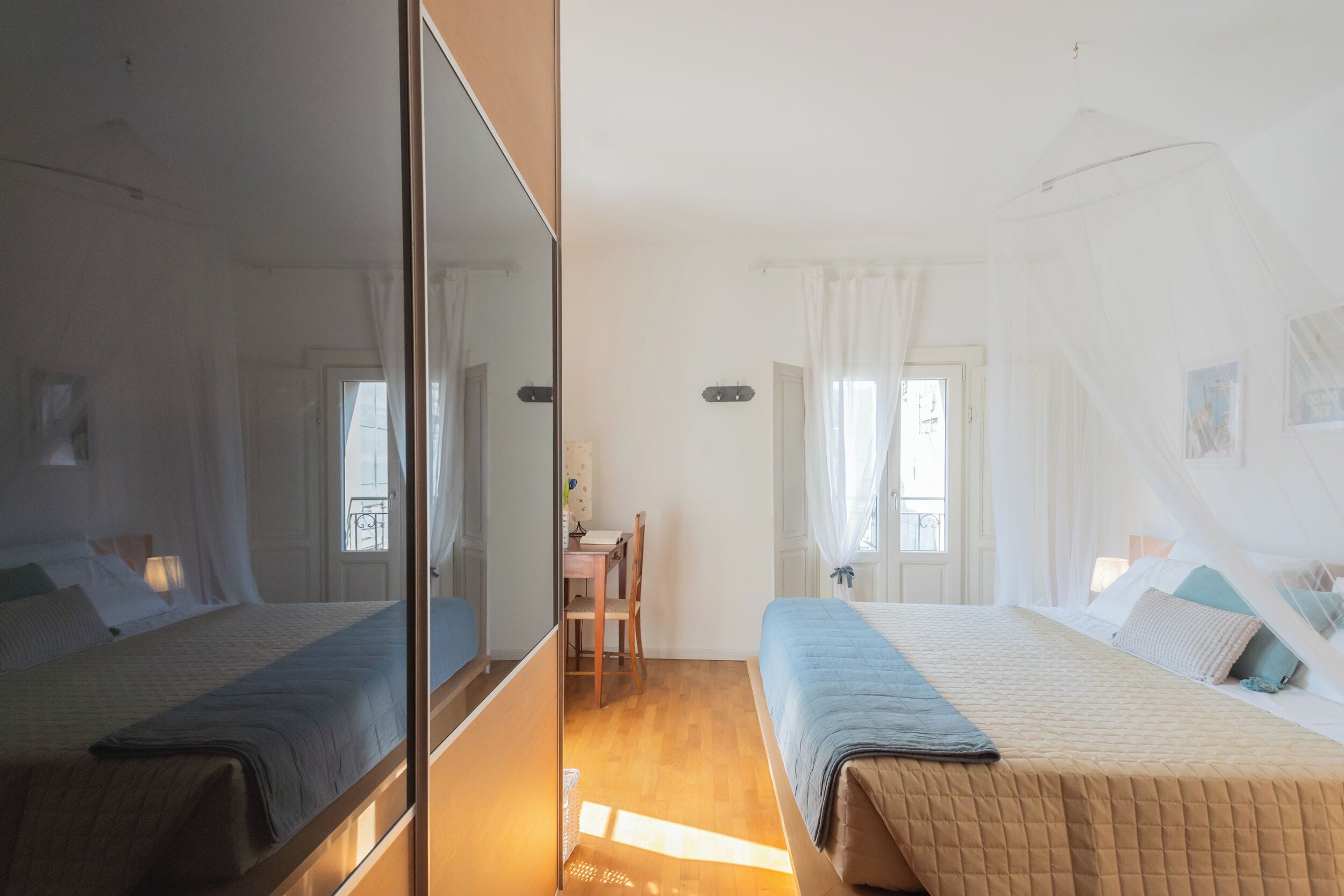 A bedroom with two beds, a desk, and a chair.