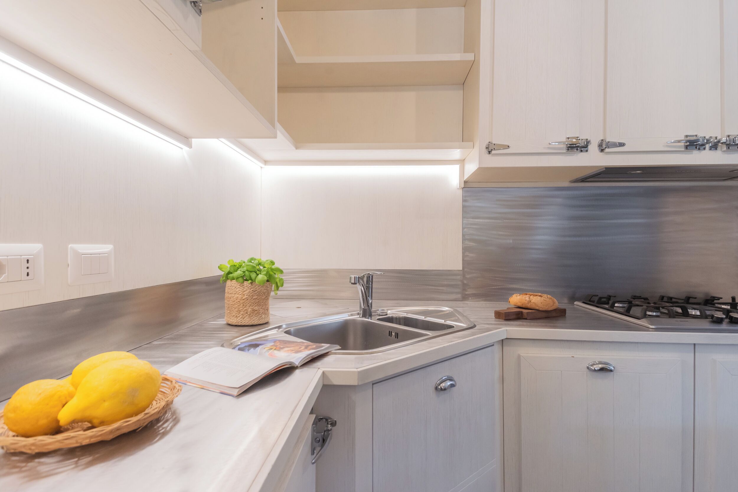 A modern kitchen with a stainless steel sink, a built-in stove, and light-colored cabinetry.