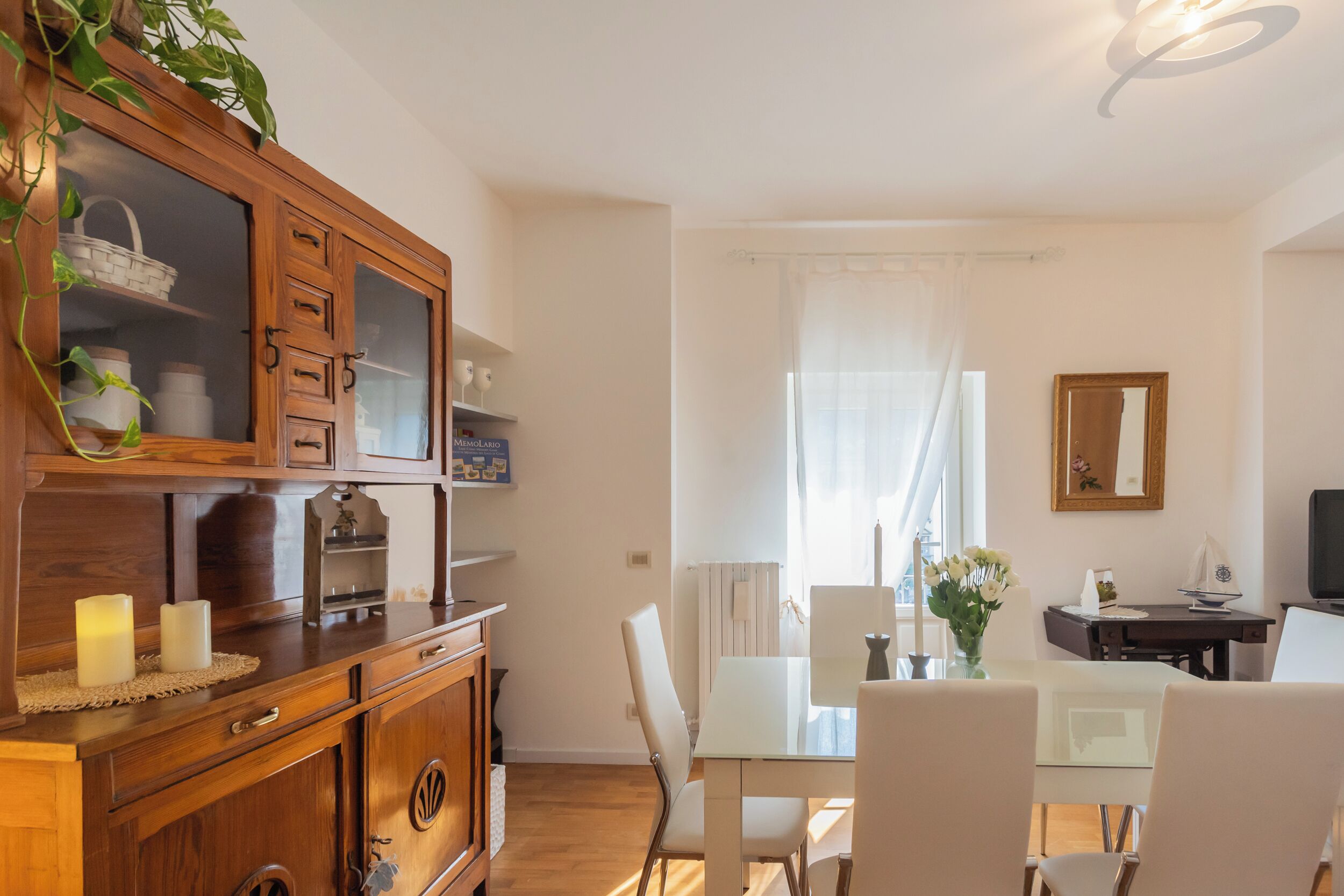 A dining area with a wooden cabinet, a table, chairs, and a view of the outdoors.