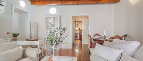 A living room with a white sofa, a coffee table with a vase, and a wooden ceiling.