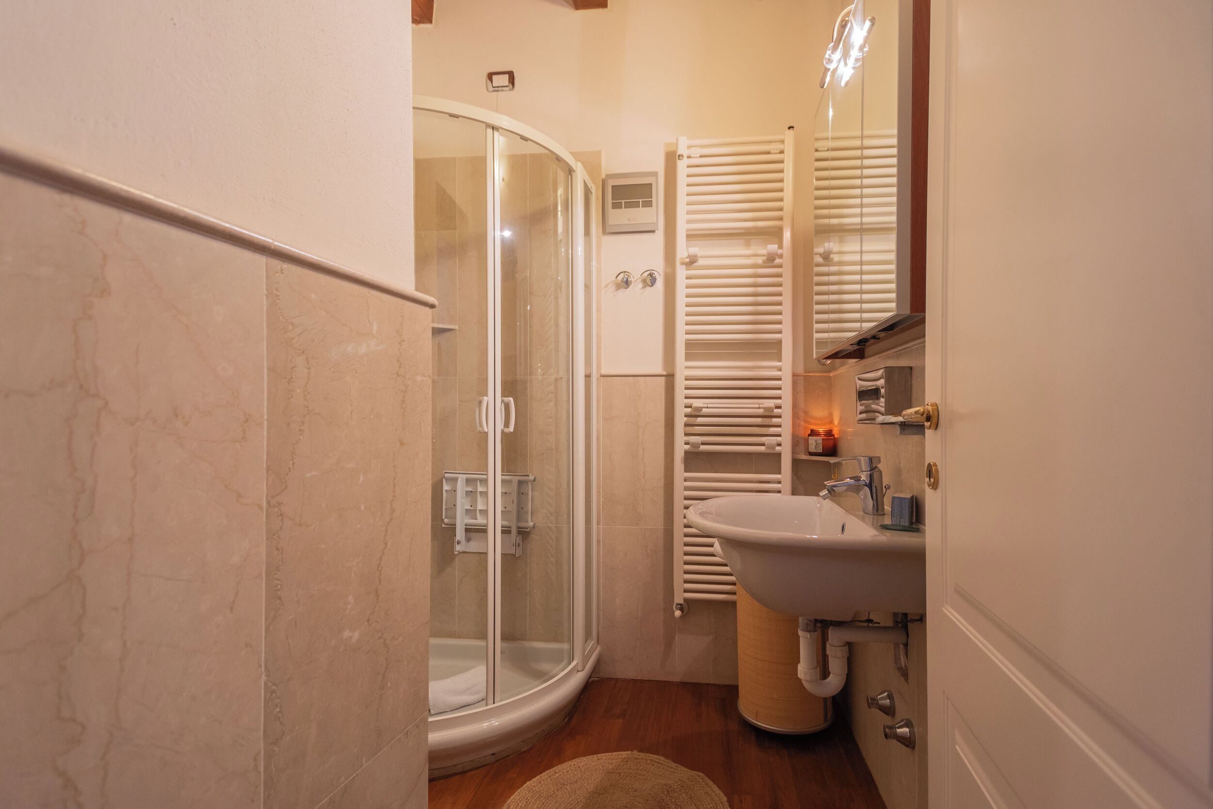 A bathroom with a glass shower enclosure, a white sink, and a towel rack.