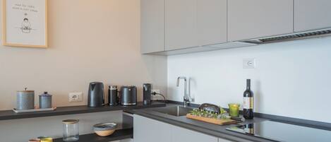 A modern kitchen with grey cabinets, a black countertop, and various kitchen appliances.