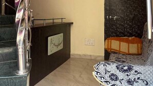 Un salon comprenant un canapé, un ventilateur de plafond, une porte ornée d’un panneau décoratif et un escalier muni d’une rampe.