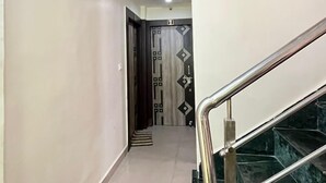 Un couloir avec un escalier en marbre, une porte ornée d’un motif géométrique et un luminaire au plafond.