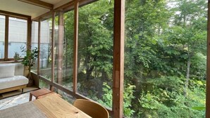 Una habitación con un ventanal grande, una mesa de madera, un sofá y una planta en maceta.