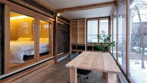 Un interior de madera con una cama, una mesa y ventanas grandes.