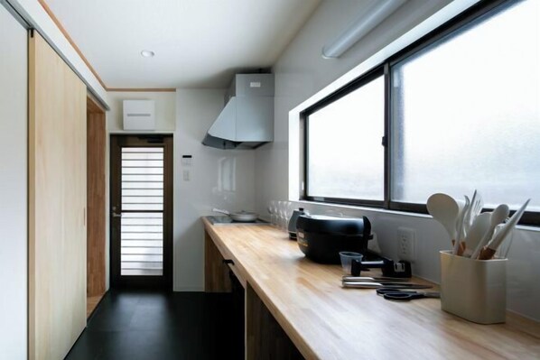 A compact kitchen with a wooden countertop, a window, and a built-in stove. - Cooee Yamanakako (Yamanakako)
