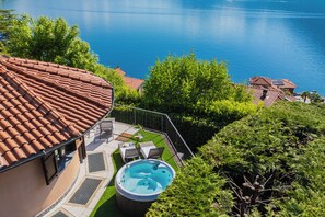 Un espace piscine aménagé sur le toit, avec un jacuzzi, entouré de verdure et offrant une vue sur une étendue d’eau.