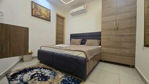 A bedroom with a bed, a wardrobe, a painting, and an air conditioning unit. - G8 Hotel (Kharar)