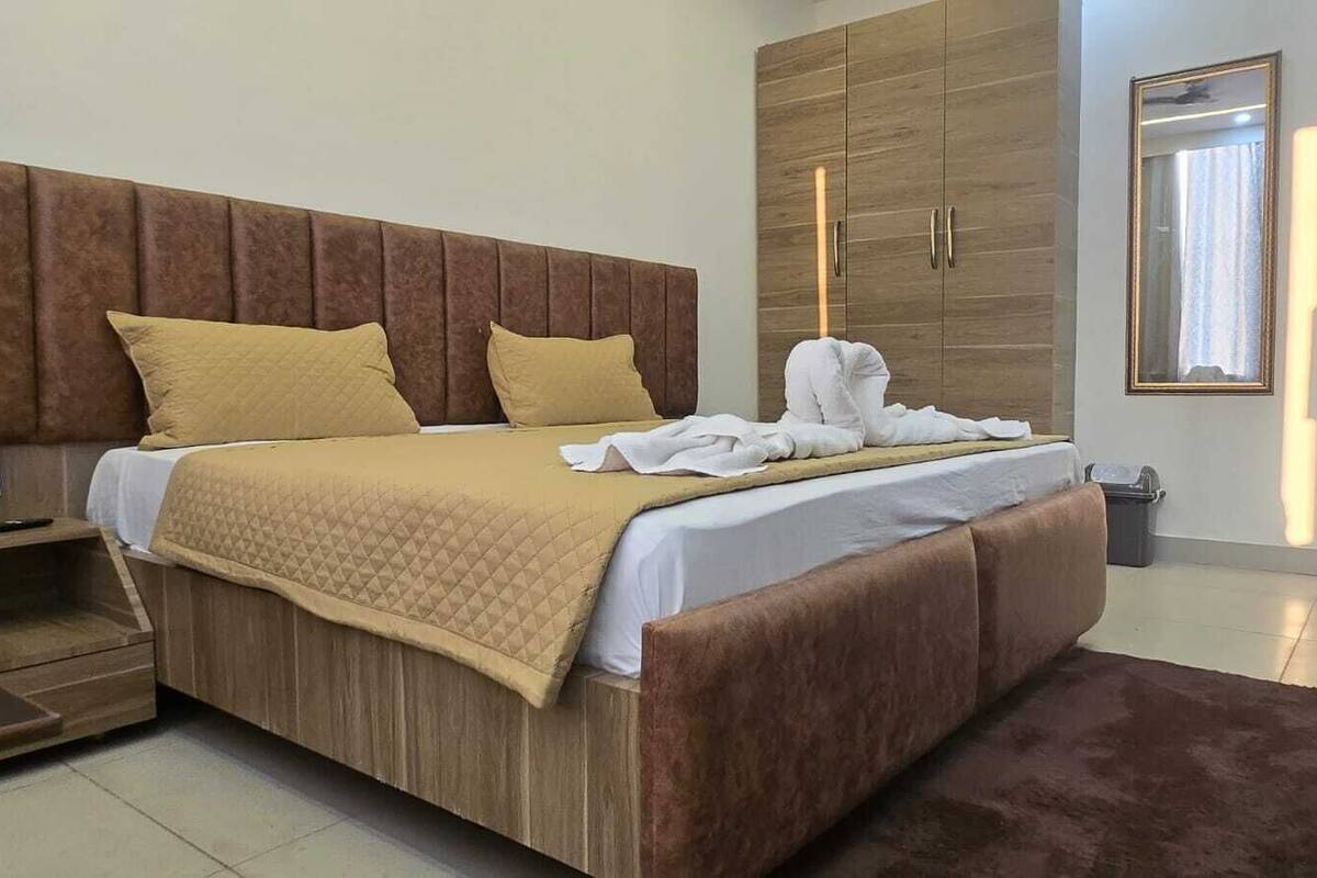 A modern bedroom with a wooden bed, a large wardrobe, and a mirror.