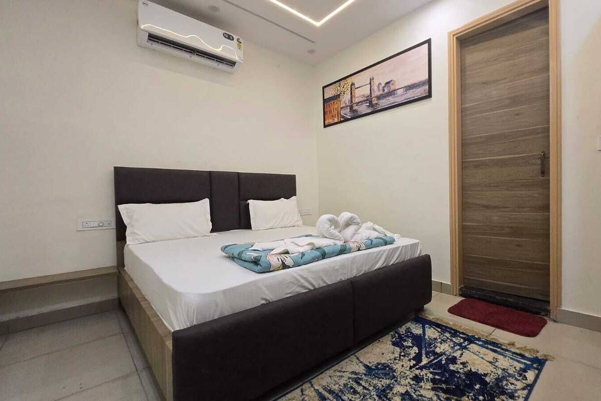 A bedroom with a bed, a headboard, a wall-mounted air conditioner, a door, and a rug.