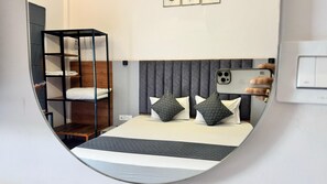 Una habitación de hotel moderna con una cama litera, una mesita de noche y un espejo grande.