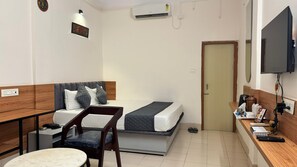 A compact hotel room with a bed, a desk, a chair, a TV, and a small table. - Hotel Insta 18 (Siliguri)