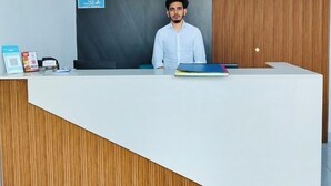A reception desk with a modern design, featuring a wooden panel and a white counter. A sign on the wall indicates a recycling bin. - Hotel Insta 18 (Siliguri)