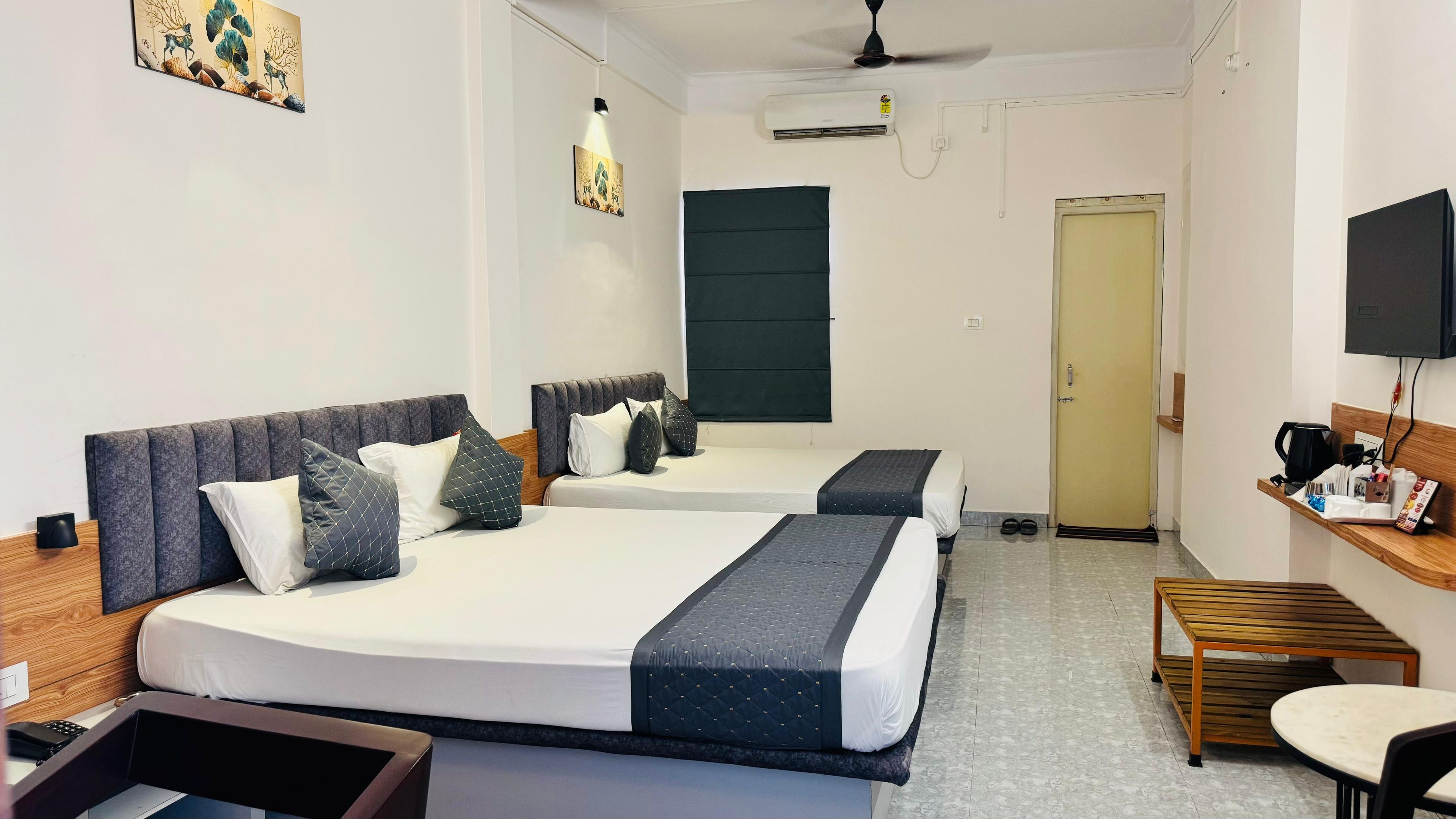 A hotel room with two beds, a desk, a chair, and a television.