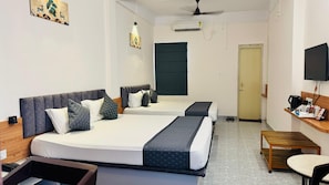 A hotel room with two beds, a desk, a chair, and a television.