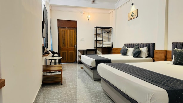 A hotel room with two beds, a desk, a chair, a wardrobe, and a wall-mounted shelf with towels. - Hotel Insta 18 (Siliguri)