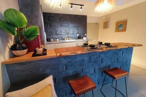 Eine moderne Küche mit Barbereich, Barhocker und einer großen Kübelpflanze.