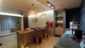 A modern kitchen with a wooden island, pendant lights, and a coffee machine.