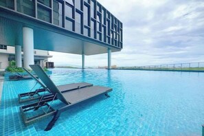A swimming pool area with lounge chairs and a modern building structure in the background. - Bali Residence Melaka by Jeffery Lam Home Management (Melaka)