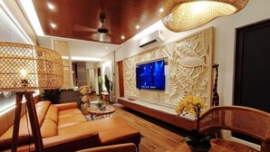 A modern living room with a sofa, chairs, a TV, and decorative wall panels.