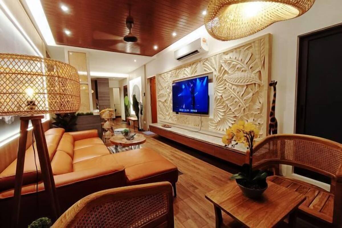 Ein modernes Wohnzimmer mit einer Couch, Sesseln, einem Fernseher und dekorativen Wandverkleidungen.