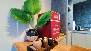 A kitchen counter with a plant, a Coca-Cola cooler, and a tray with jars.