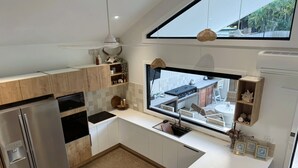 Une cuisine moderne dotée d’une grande fenêtre, d’appareils électroménagers en acier inoxydable et d’armoires en bois.