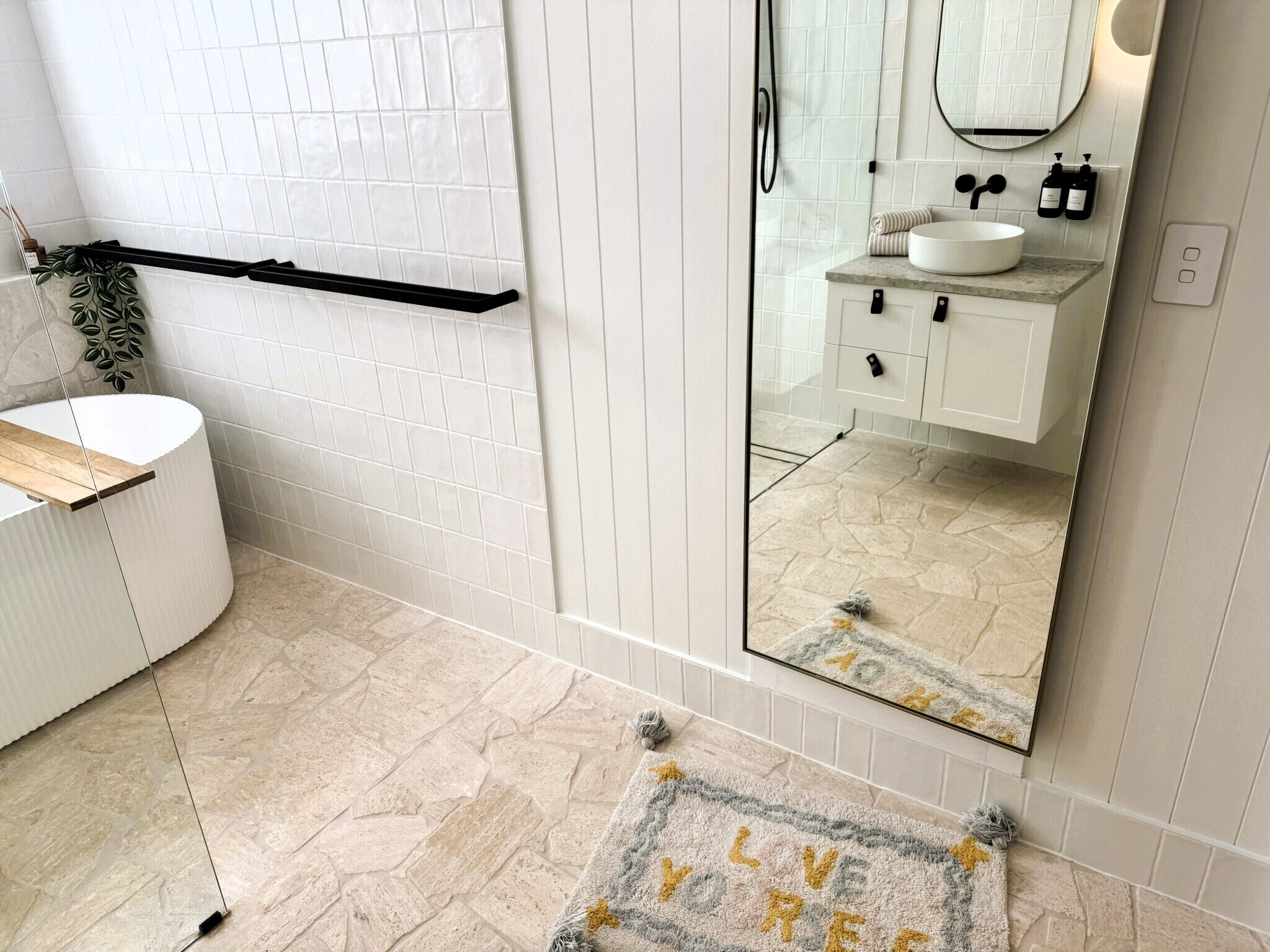 Une salle de bain moderne avec un lavabo blanc, un miroir et un porte-serviettes.