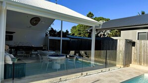 Un espace piscine extérieur abrité, doté d’un jacuzzi, de chaises longues et d’un barbecue.