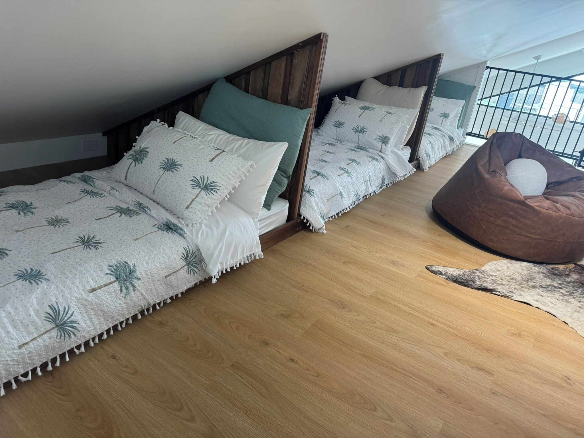 Ein Schlafzimmer mit drei Holzbetten, einem braunen Sitzsack und Holzboden.