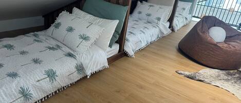 Ein Schlafzimmer mit drei Holzbetten, einem braunen Sitzsack und Holzboden.