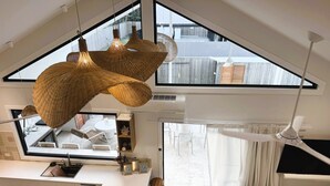 Une cuisine moderne dotée d’une grande fenêtre, d’un coin repas avec des chaises et d’un ventilateur de plafond.