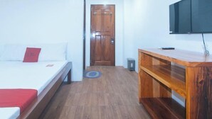 A room with a bed, a wooden console table, a television, and a door.