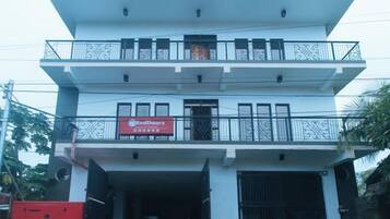 A multi-story building with a red sign, balconies, and a garage entrance.