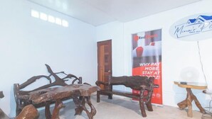 A room with a rustic wooden bench and a small table. A red banner with white text is visible in the background.