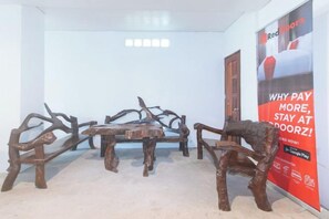 A room with a wooden table and benches made from tree branches, a white wall, and a door. - RedDoorz @ Minas Place 2 Banez Ville Tacloban (Tacloban)