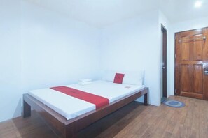 A single bed with a red accent, a wooden door, and a small rug on a wooden floor. - RedDoorz @ Minas Place 2 Banez Ville Tacloban (Tacloban)