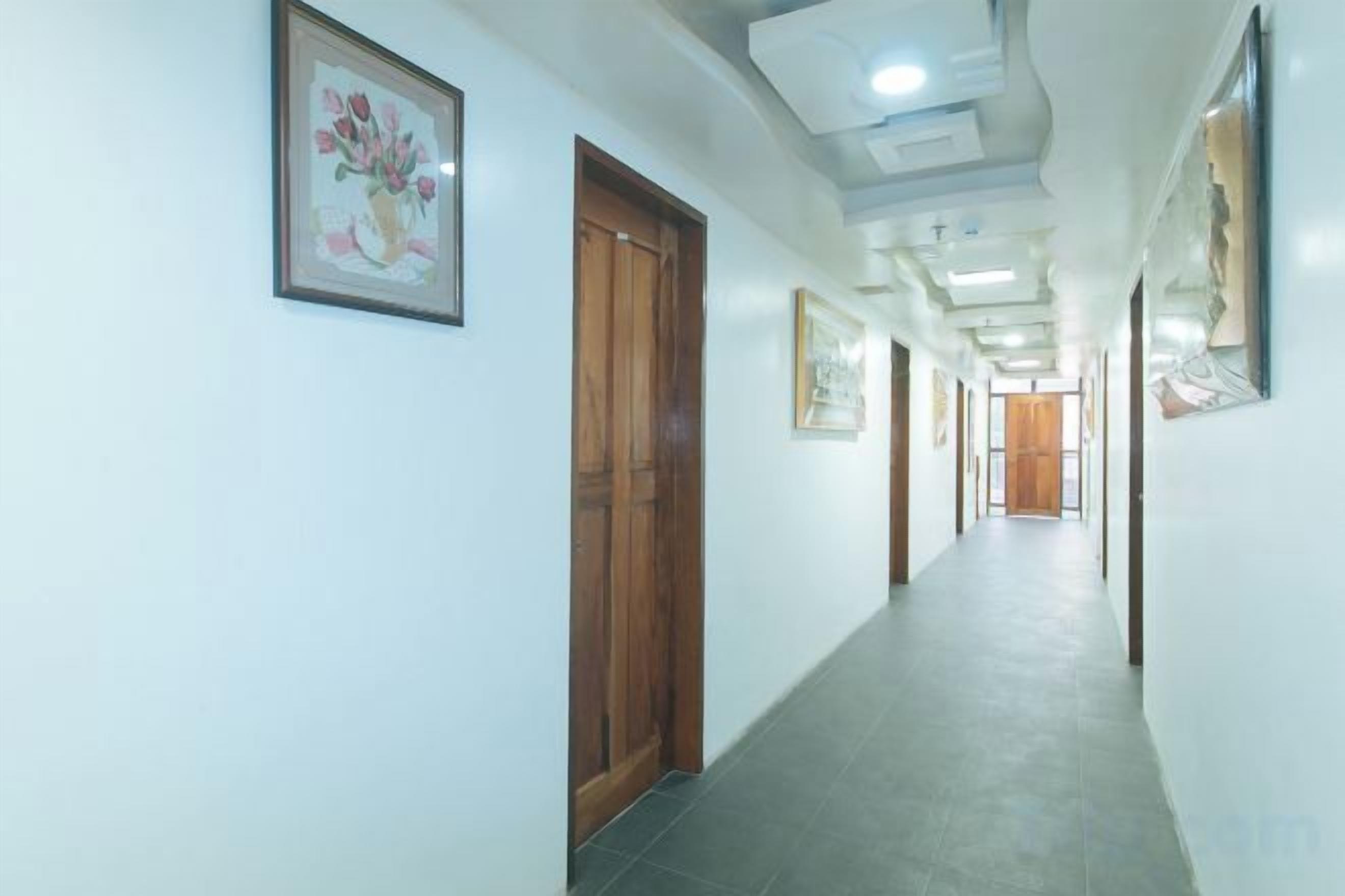 A hallway with doors, framed artwork, and a tiled floor.