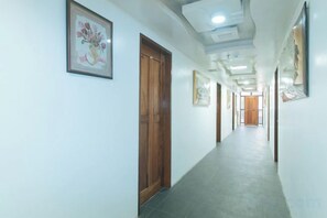 A hallway with doors, framed artwork, and a tiled floor. - RedDoorz @ Minas Place 2 Banez Ville Tacloban (Tacloban)