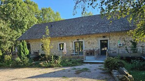 Ein Steinhaus mit einem Schotterweg und einer Holzterrasse.