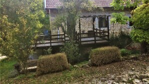Ein rustikales Steinhaus mit einer Holzbrücke und einer Holzpergola.