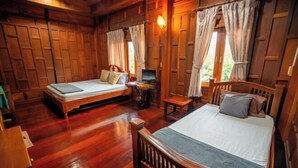 A wooden cabin with two single beds, a small table, and a TV. - Ban Suan Bang Toei Villa (Sam Phran)