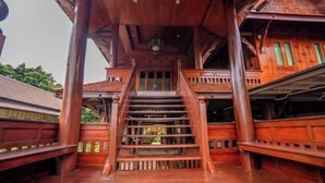 A wooden staircase with a traditional design, leading to an upper level. - Ban Suan Bang Toei Villa (Sam Phran)