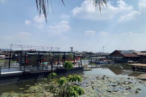 A riverside view with a restaurant, boats, and a bridge. - Ban Suan Bang Toei Villa (Sam Phran)