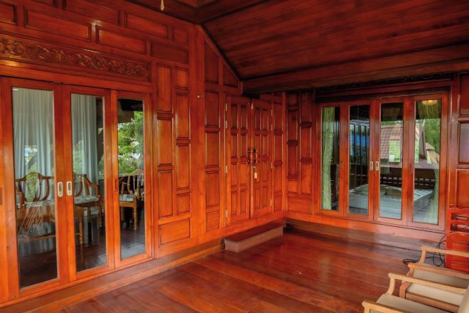 Amplia habitación con paneles de madera y grandes puertas correderas de vidrio que dan a un área exterior.