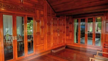 Amplia habitación con paneles de madera y grandes puertas correderas de vidrio que dan a un área exterior.