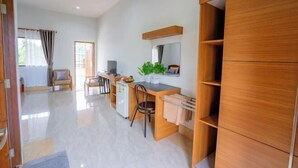 A modern hotel room with a wooden desk, a small kitchenette, a seating area with a chair, and a large wardrobe. - Ban Suan Bang Toei Villa (Sam Phran)