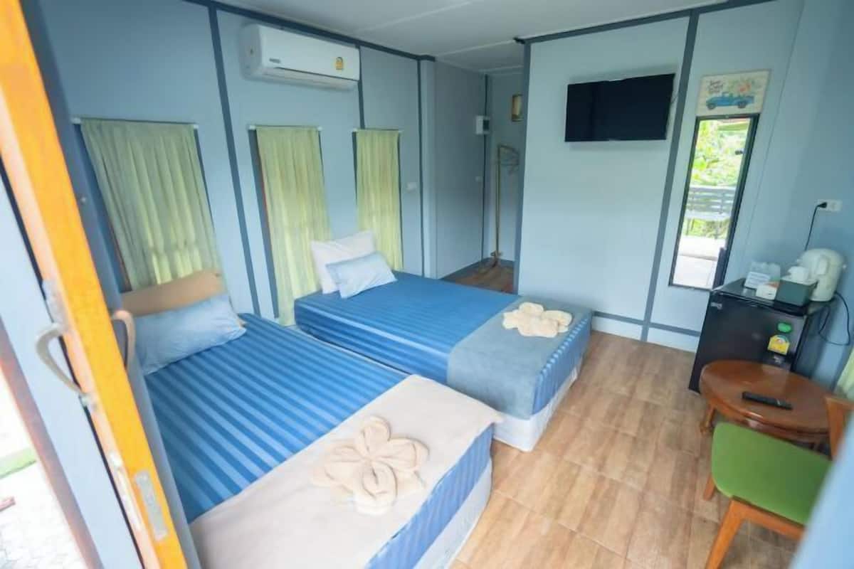 Quarto com duas camas, uma escrivaninha e uma cadeira.