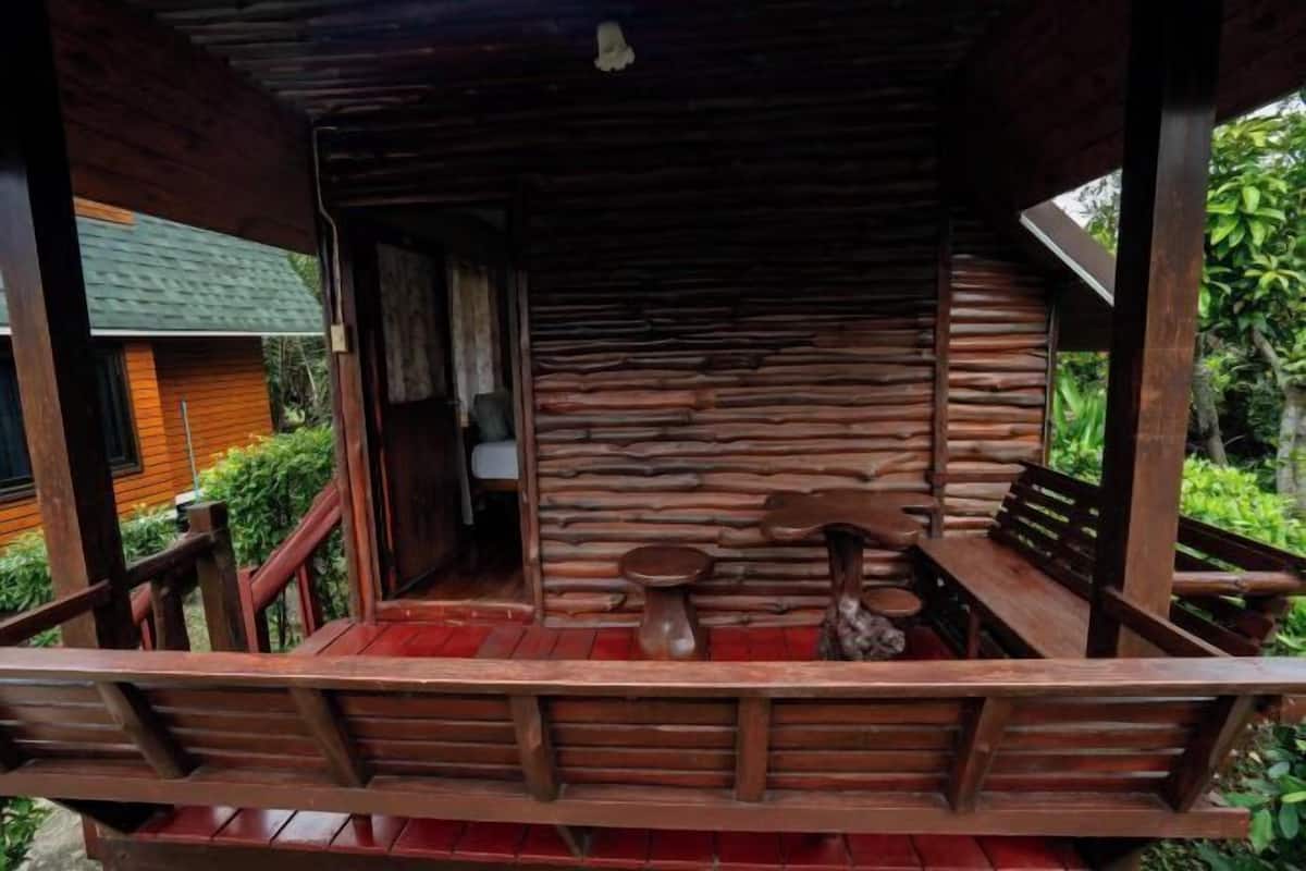 Um deck de madeira com uma mesa e cadeiras, cercado por uma cerca de madeira.